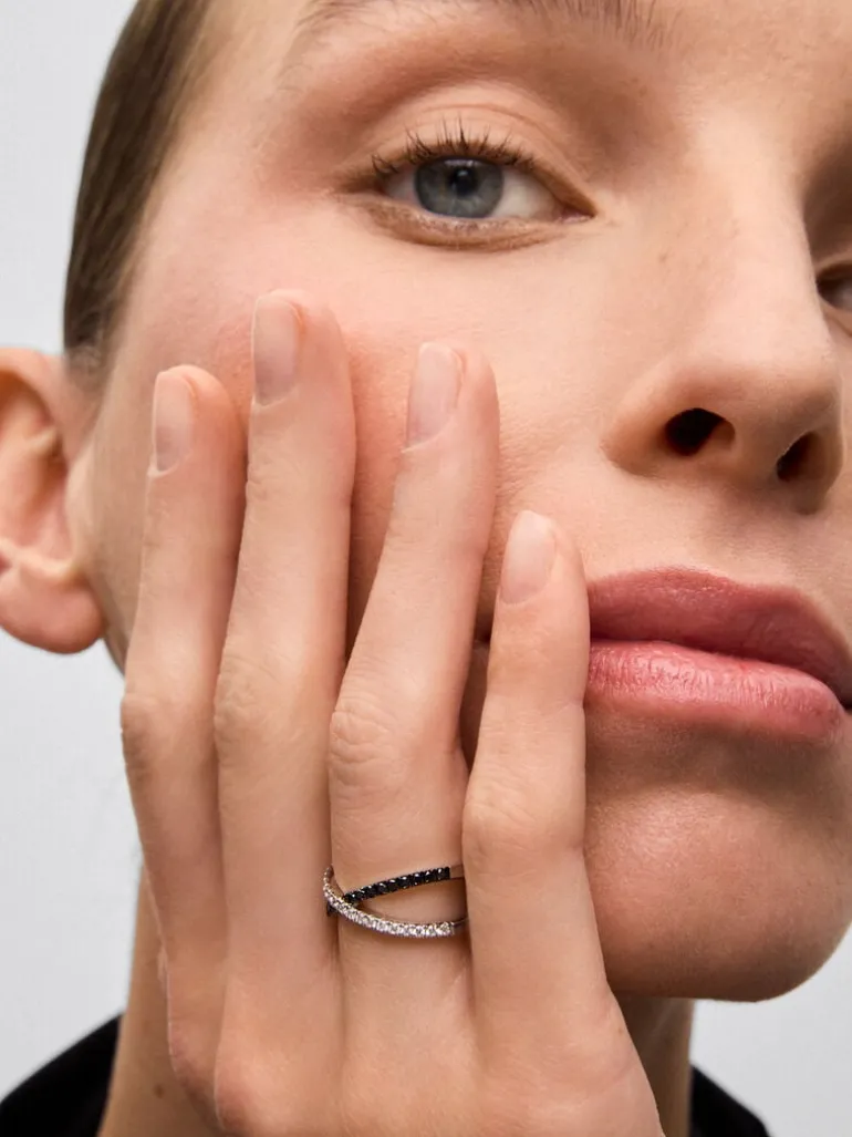 Anillo cruzado de oro blanco de 18K con 21 diamantes en talla brillante con un total de 0,25 cts y 18 diamantes negros en talla brillante con un total de 0,24 cts