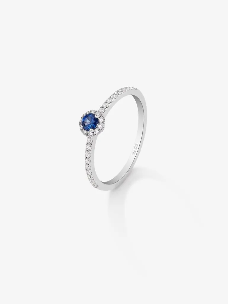Anillo de oro blanco de 18K con zafiro azul en talla brillante de 0,15 cts y orla y brazo de 28 diamantes en talla brillante con un total de 0,2 cts