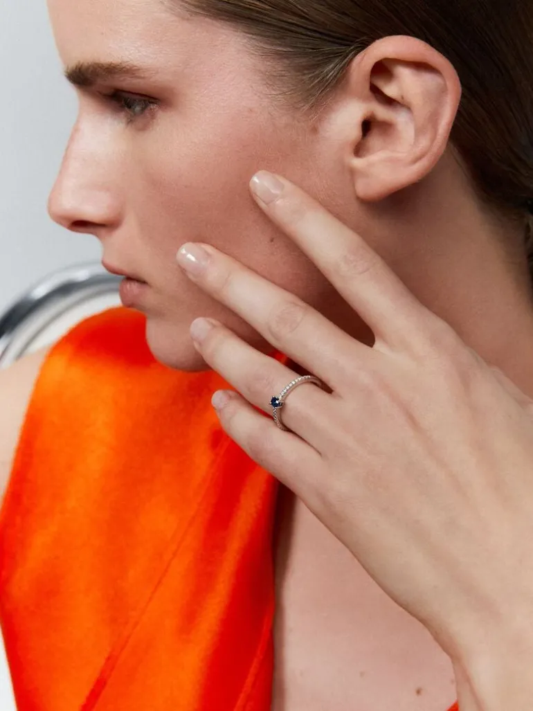 Anillo de oro blanco de 18K con zafiro azul en talla oval de 0,3 cts y brazo de 16 diamantes en talla brillante con un total de 0,2 cts