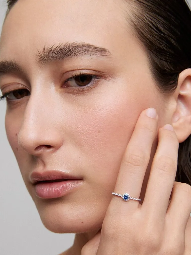 Anillo de oro blanco de 18K con zafiro azul en talla brillante de 0,15 cts y orla y brazo de 28 diamantes en talla brillante con un total de 0,2 cts