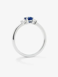 Anillo tresillo de oro blanco de 18K con zafiro azul en talla oval de 0,69 cts y 2 diamantes en talla brillante con un total de 0,16 cts