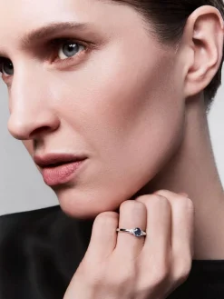 Anillo tresillo de oro blanco de 18K con zafiro azul en talla oval de 0,48 cts y 2 diamantes en talla brillante con un total de 0,24 cts