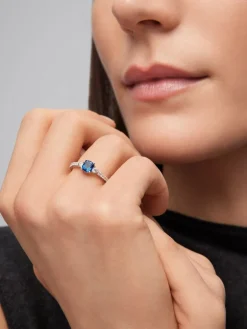 Anillo tresillo de oro blanco de 18K con zafiro azul cornflower en talla cushion de 1,09 cts y 16 diamantes en talla brillante con un total de 0,28 cts