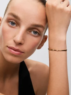 Pulsera r&iacute;gida de oro amarillo de 18K con 3 diamantes en talla brillante con un total de 0,07 cts